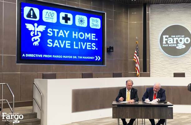 Fargo Mayor Dr. Tim Mahoney and West Fargo Commission President Bernie Dardis sign their respective Stay Home. | Save Lives. directives