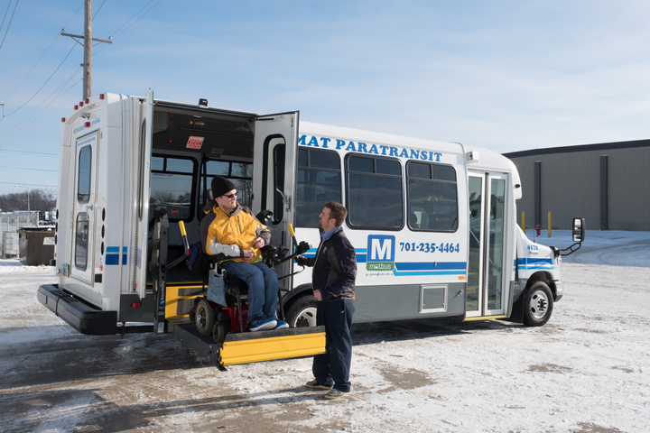 Fargo's new Transit Director Jordan Smith helps a MATBUS rider off a Paratransit bus.