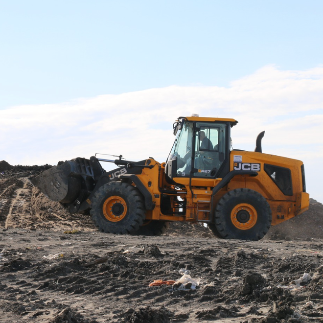 A yellow construction scooper moving earth at a work site.