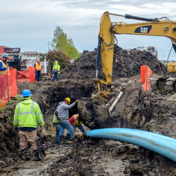 A construction machine and workers digging underground at a work site.