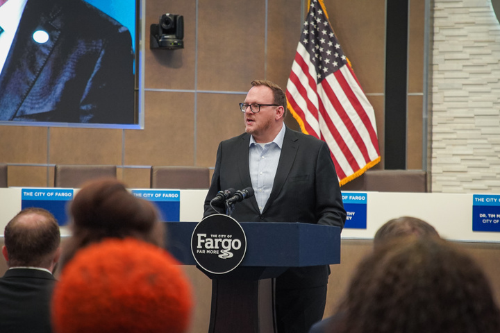 Mayor Josh Boschee stands at a podium as he addresses a gathering in the Fargo City Commission Chambers in City Hall.
