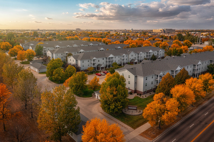 Apartment complex with fall trees and sky.